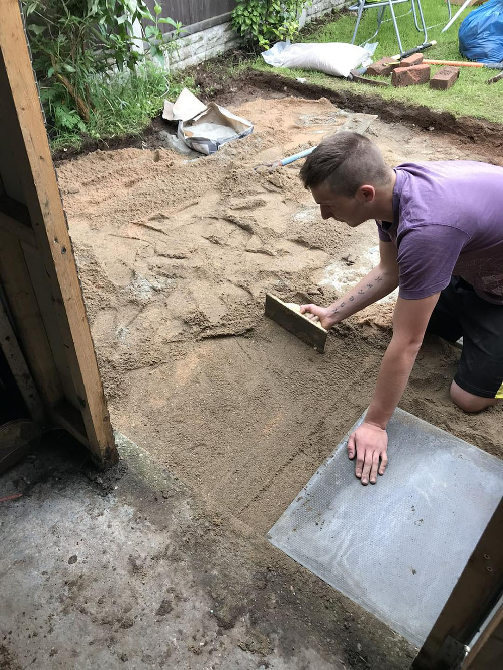 man spreading sand for paving